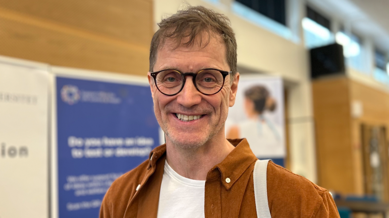 Man med glasögon ler mot kameran.