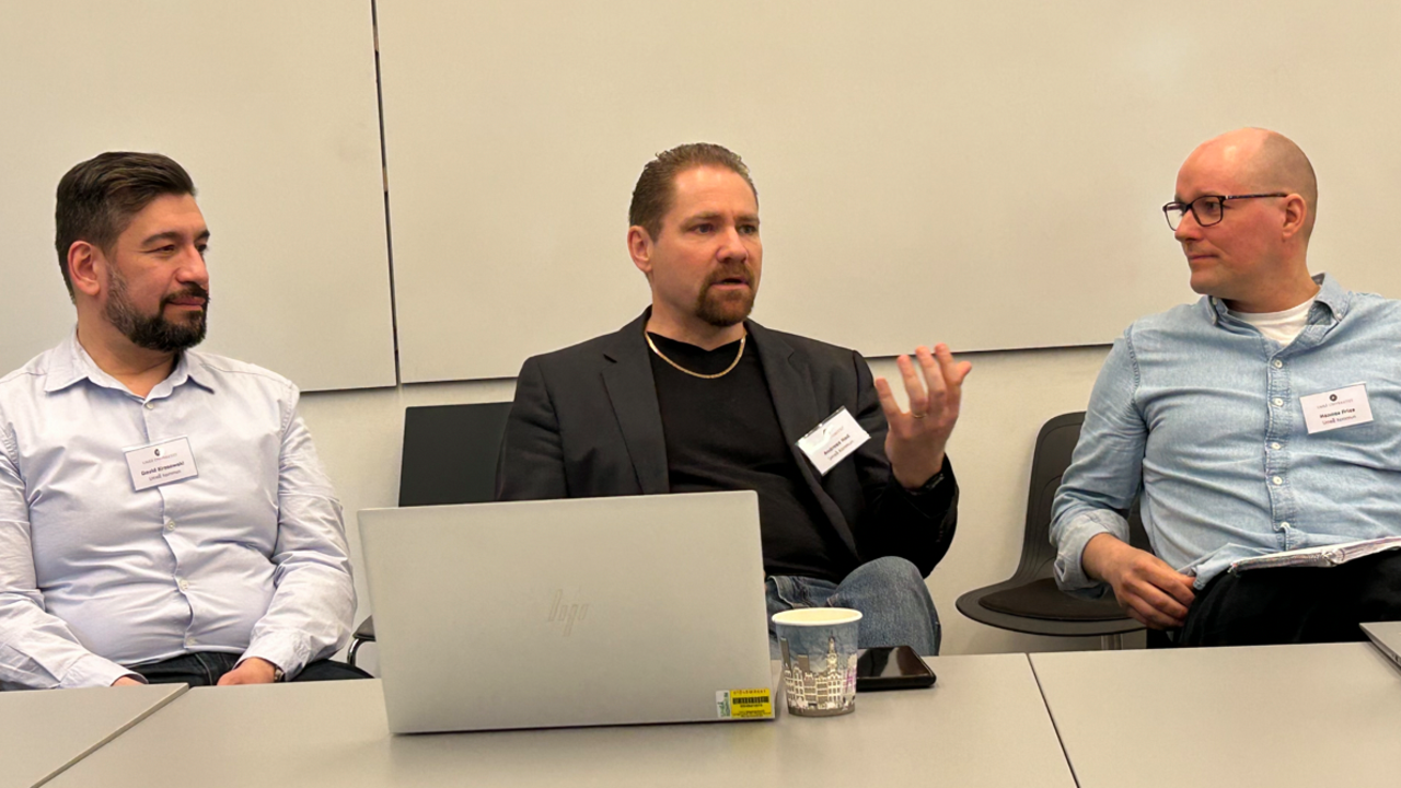 En man som pratar, flankerad av två andra personer.