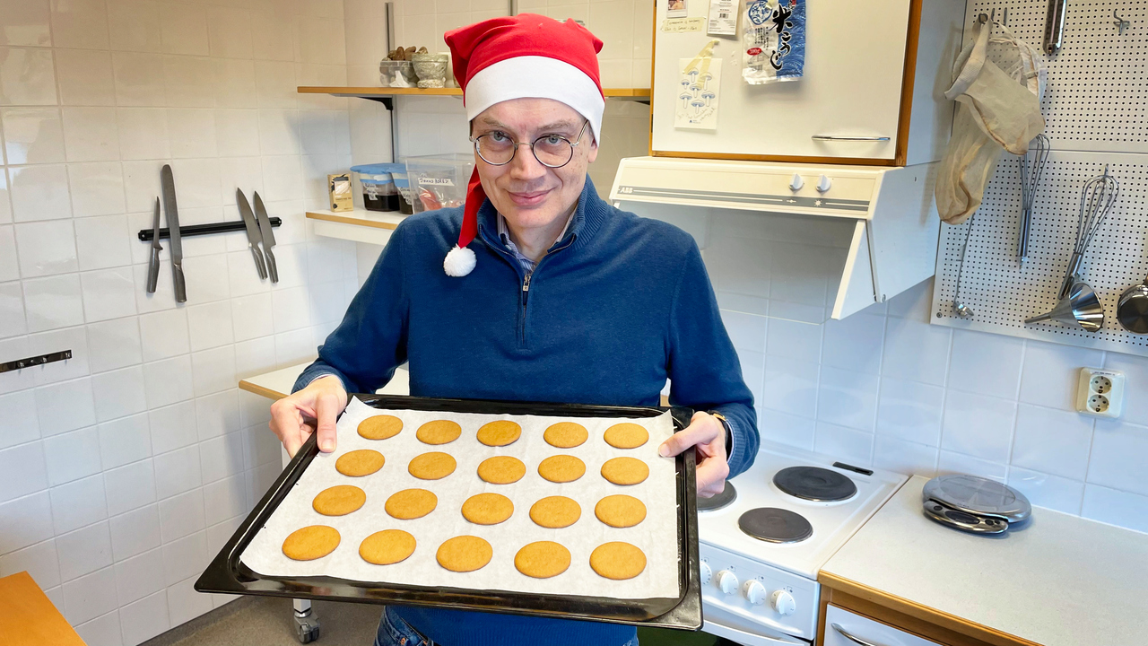 En man håller i en plåt pepparkakor i ett kök