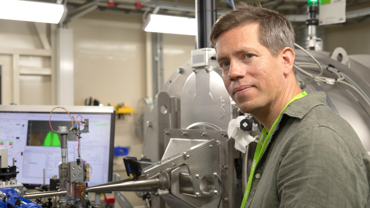 En man i halvfigur med experimentutrustning i bakgrunden.