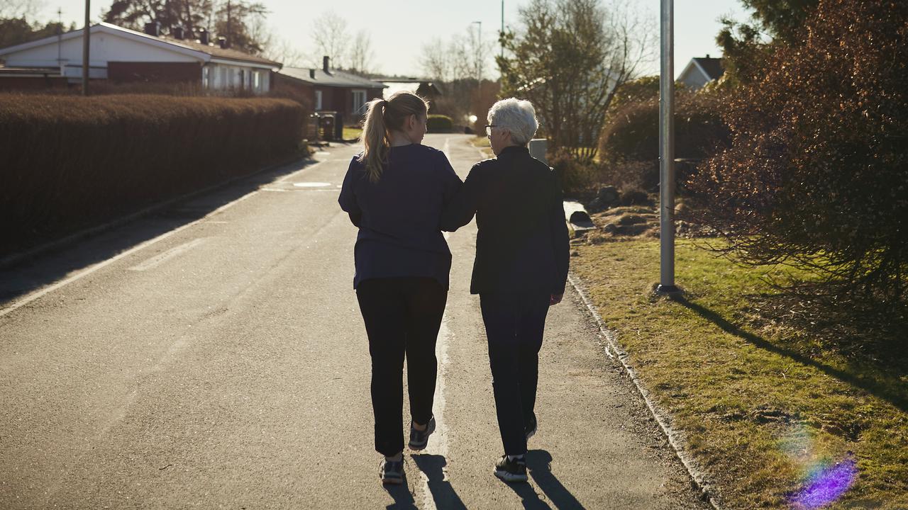 Äldre och yngre kvinna promenerar bort från fotografen