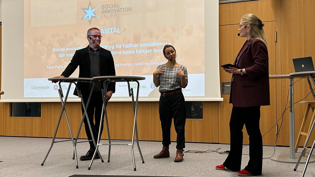 En grupp människor som står på en scen framför en projektorduk.