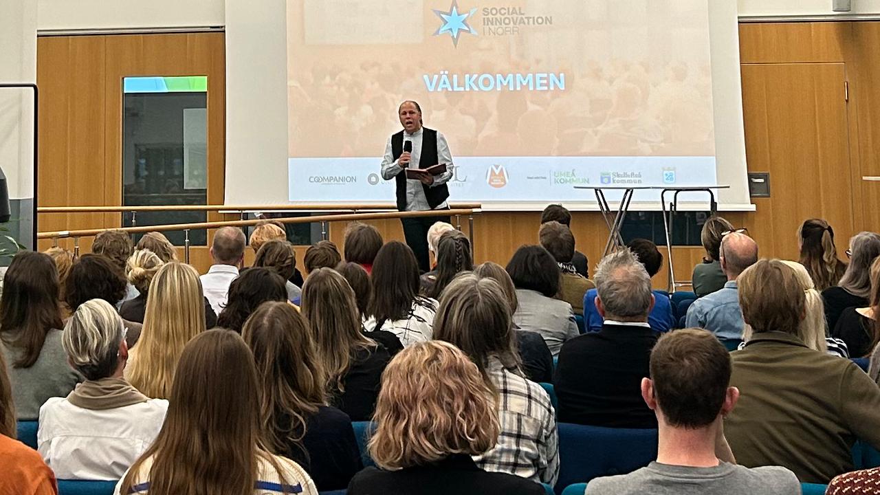 Man står på scen och pratar inför stor folkmassa.