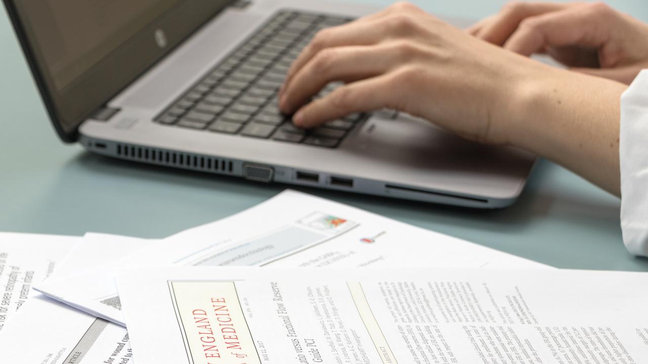 Artiklar och hand som skriver på bärbar dator