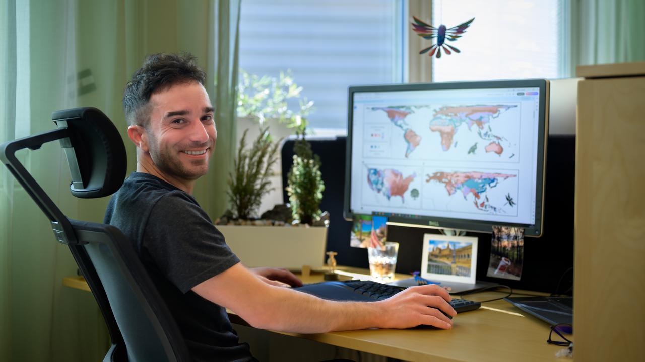 En man sitter vid ett skrivbord med en dator.