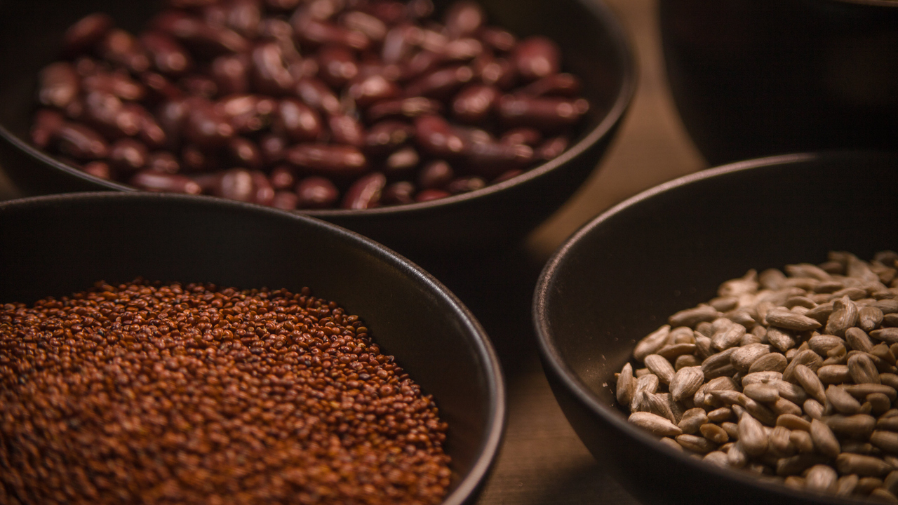 Bönor och frön i skålar på ett bord.