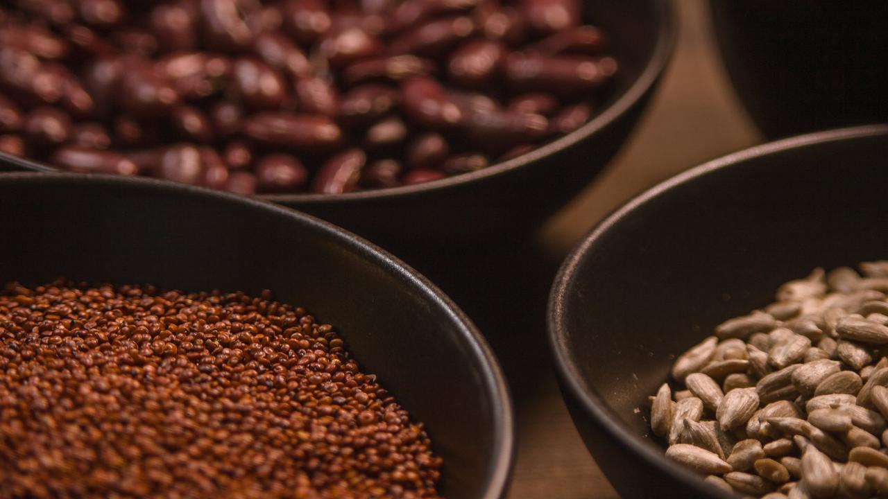 Bönor och frön i skålar på ett bord.