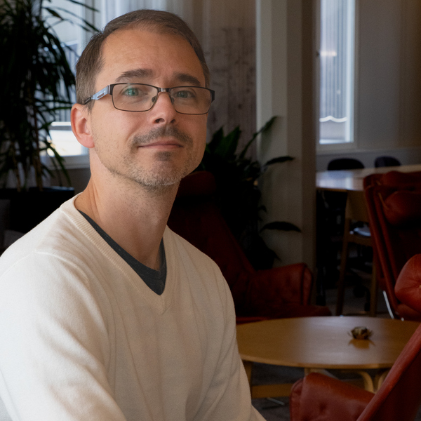 En man med glasögon sitter vid ett bord.