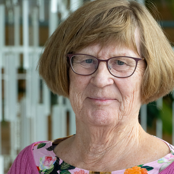 En kvinna med glasögon och rosa tröja.