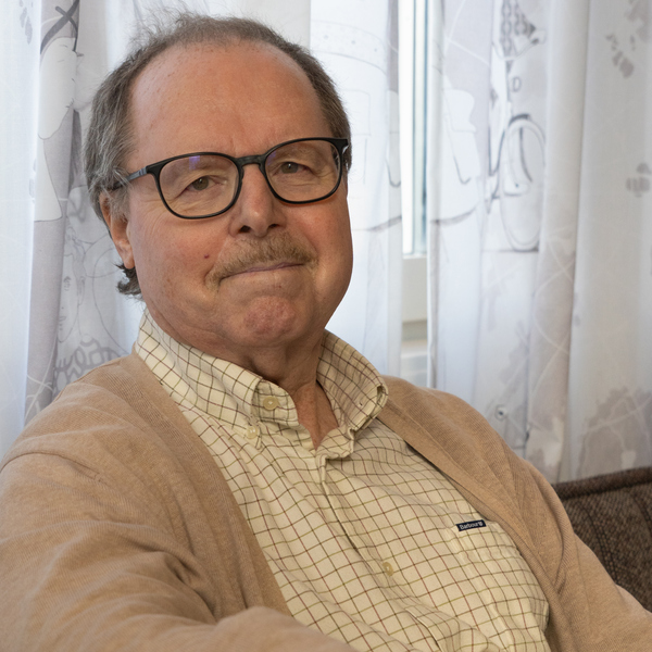 En man med glasögon sitter i en soffa.