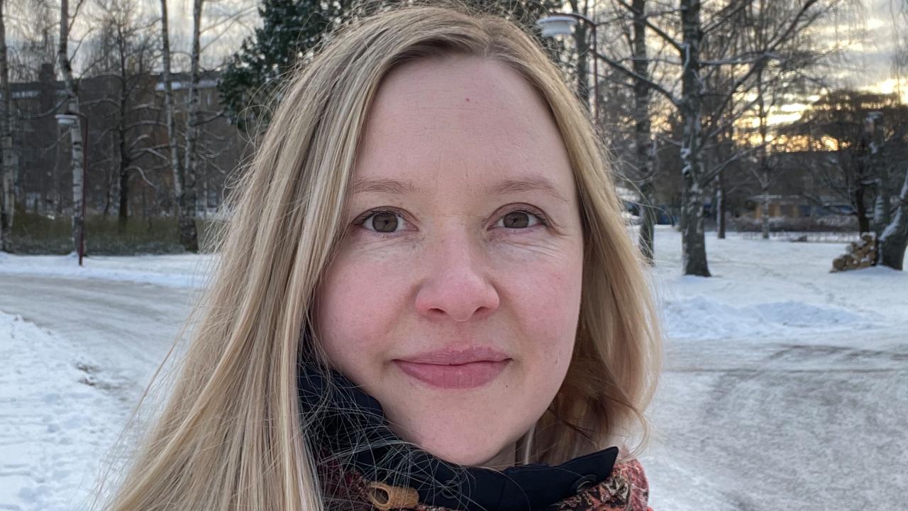 En kvinna med långt blont hår står i snön.