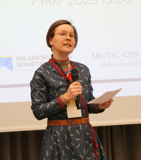 Elle Merete Omma håller i en mikrofon och pratar.