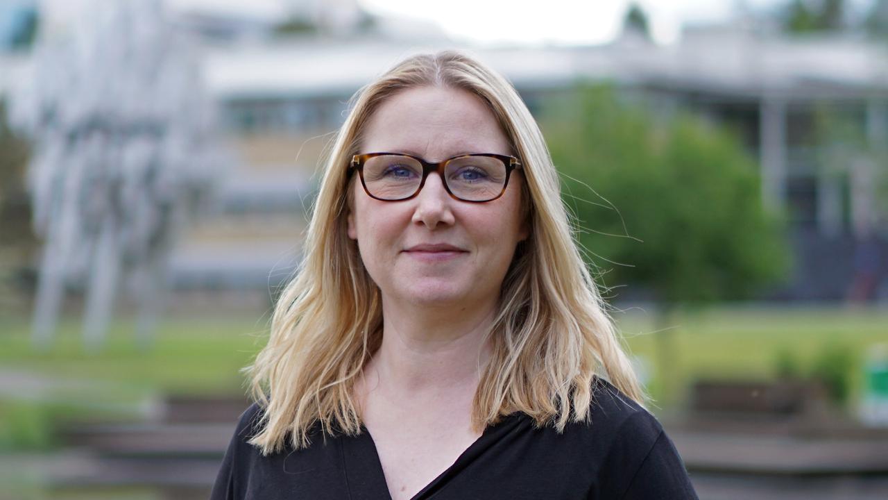 En kvinna med glasögon står framför en damm.