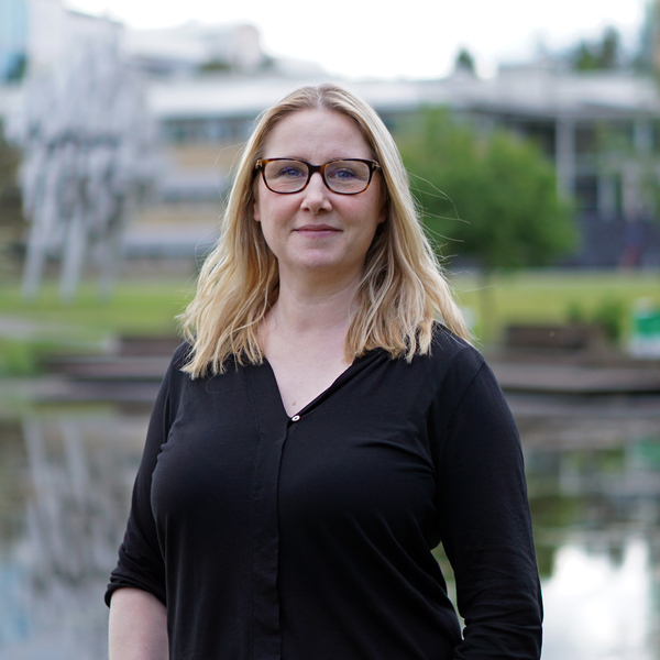 En kvinna med glasögon står framför en damm.