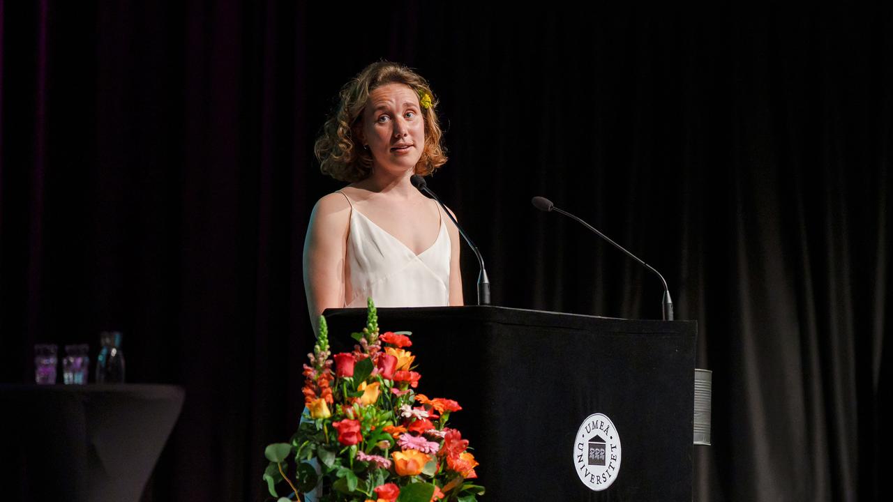 Studenttalare står på ett podium framför en mikrofon.