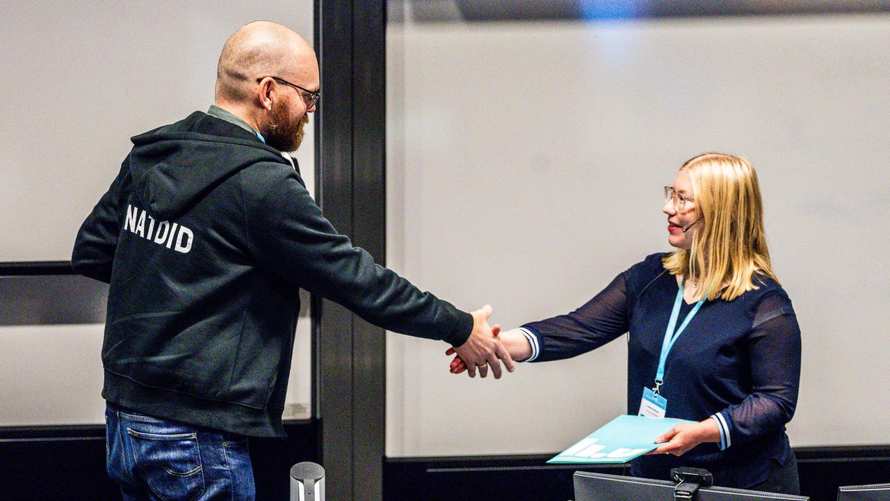 En man och en kvinna skakar hand på ett kontor.