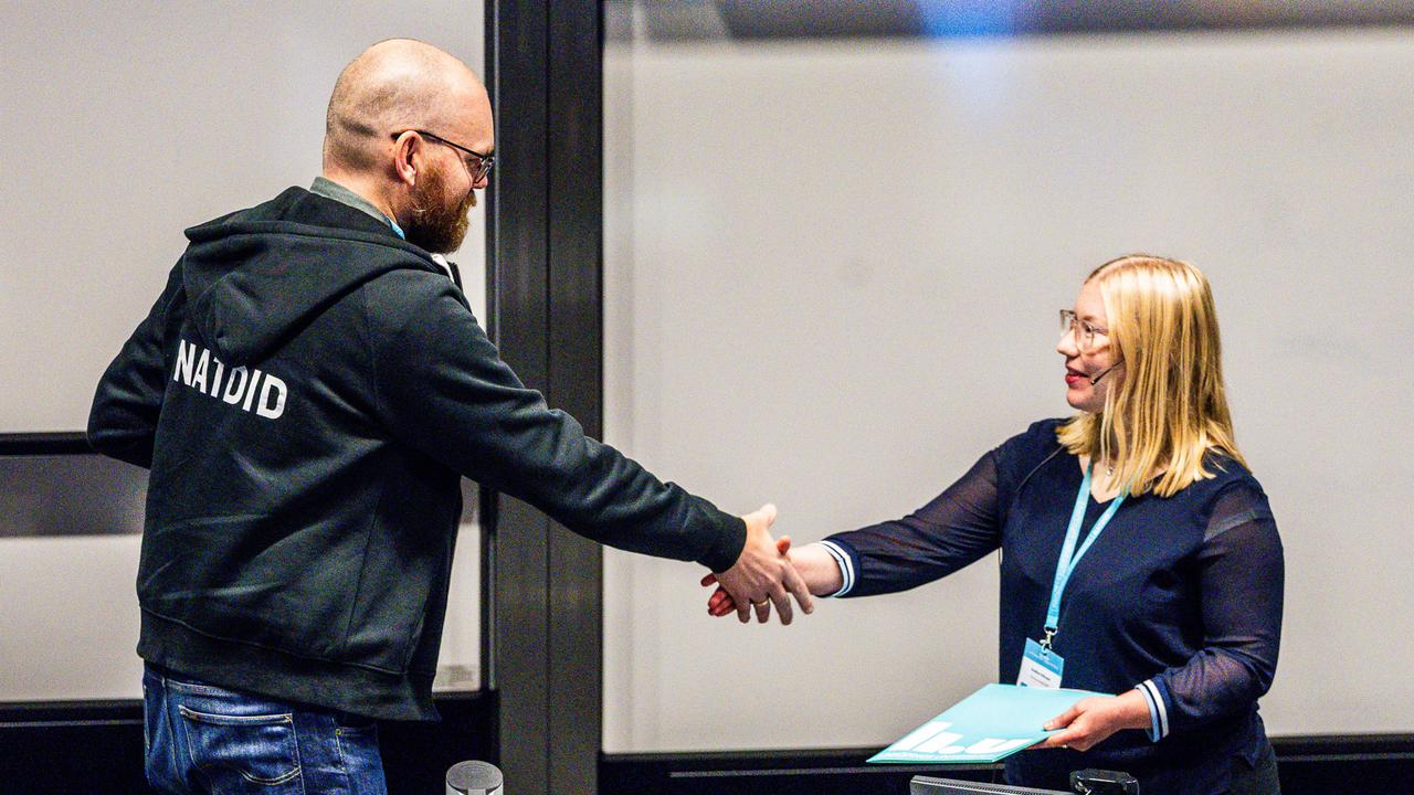 En man och en kvinna skakar hand på ett kontor.