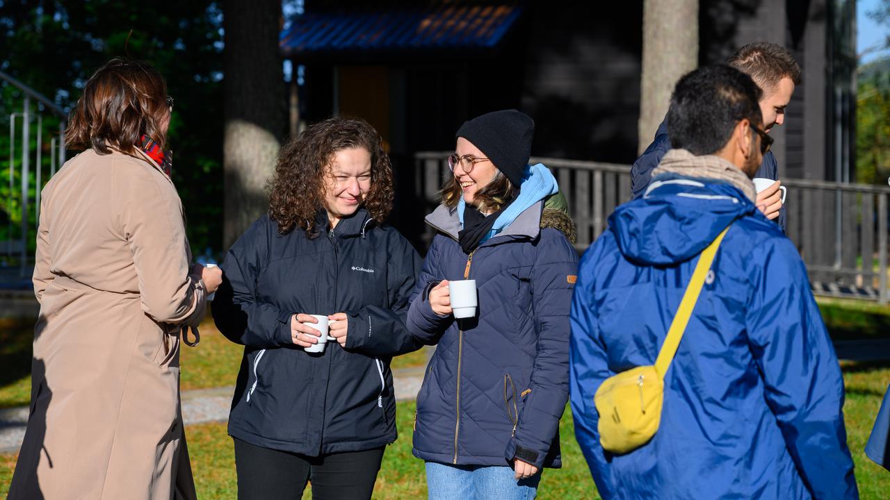 A group of people stand outside drinking out of mugs