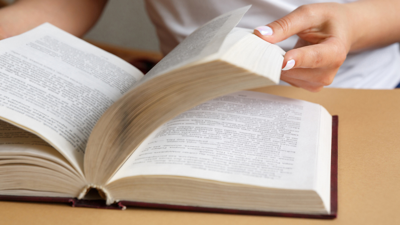 Närbild på händer som bläddrar i en bok.