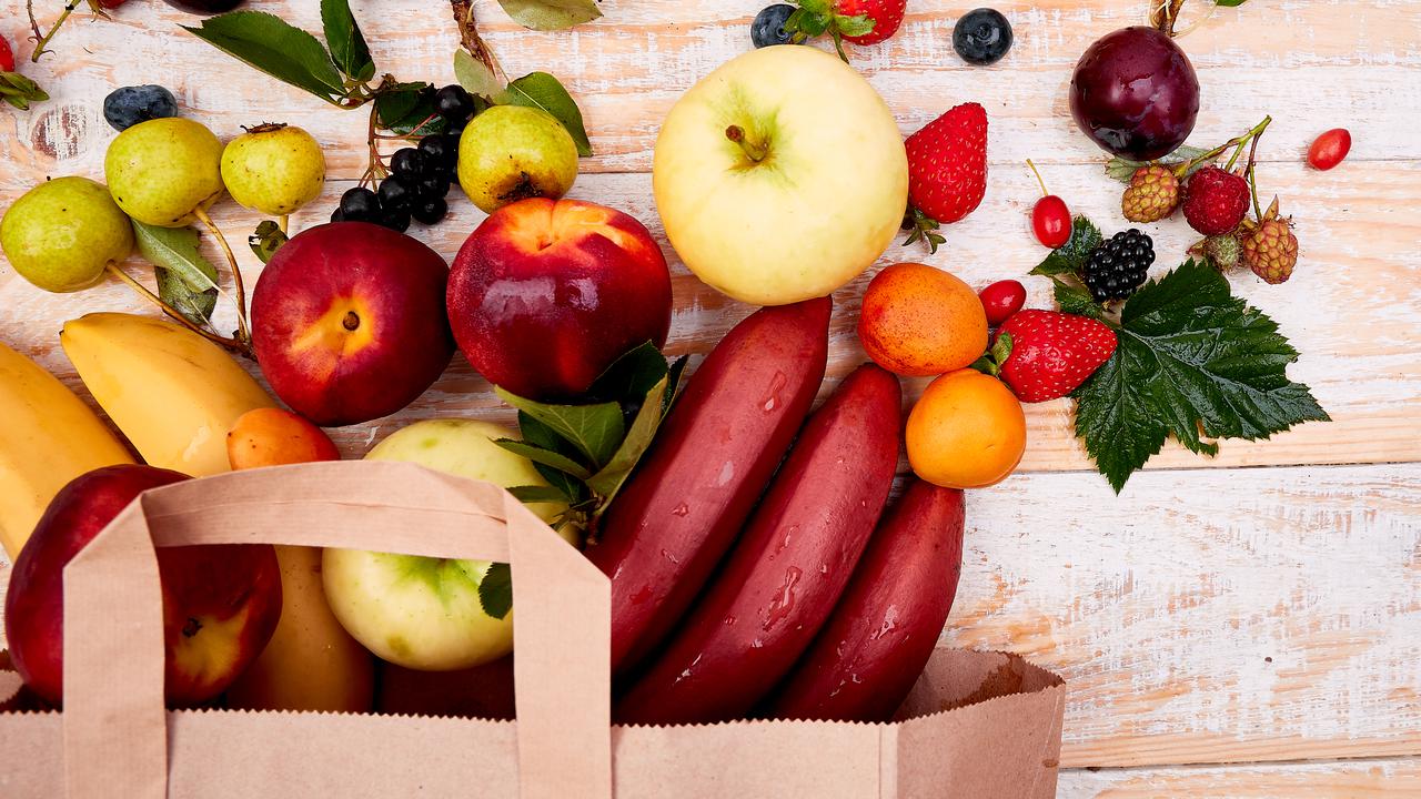 Frukt och bär hällda ur en papperspåse på ett bord. Nyttiga livsmedel.