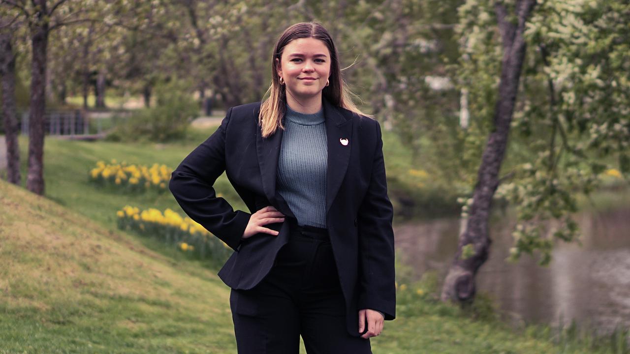 En kvinna i svart kostym står framför en flod.