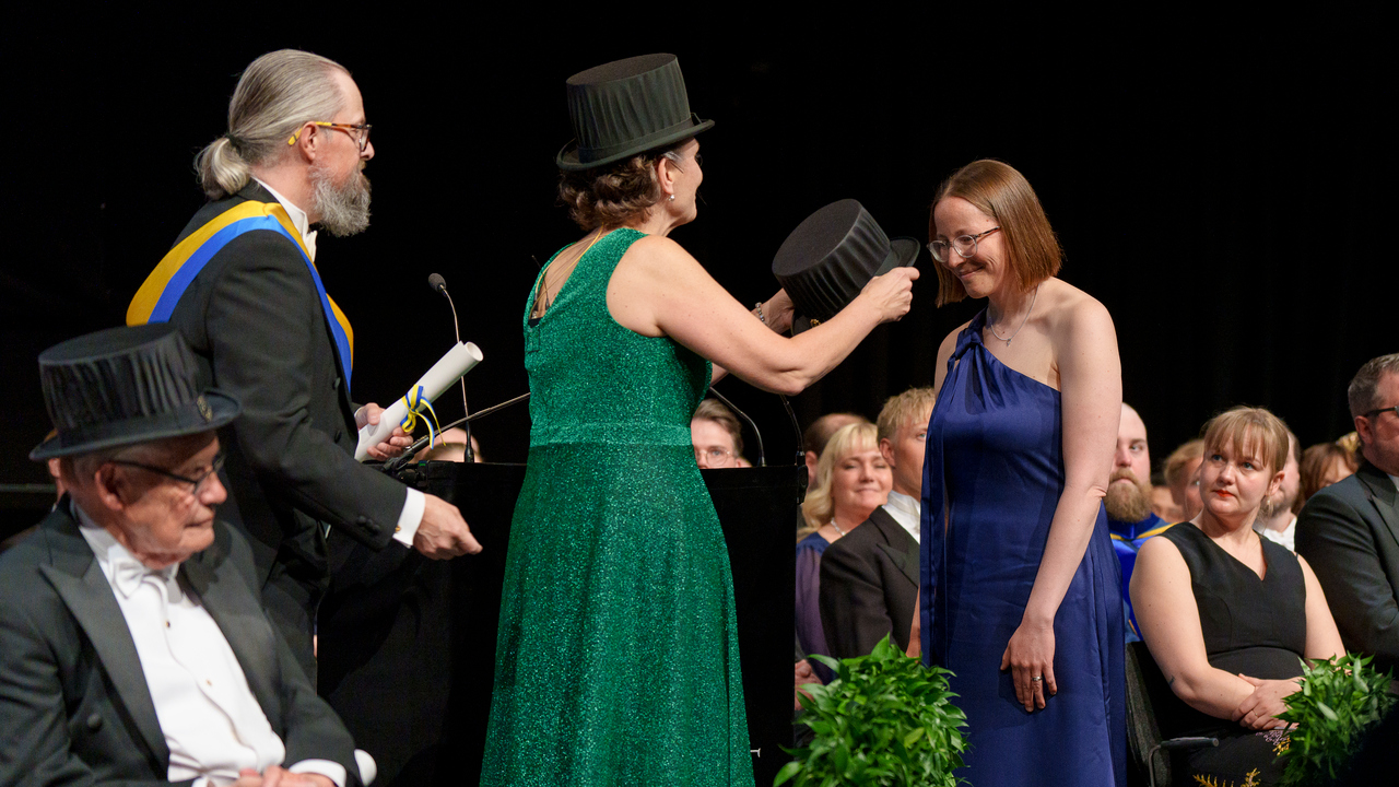 Kvinna sätter doktorshatt på annan kvinna,