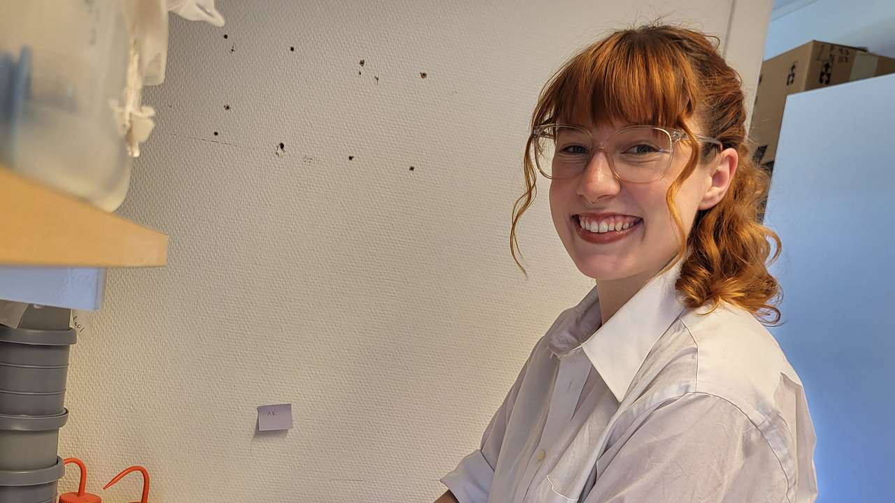 En ung glad kvinna arbetar i ett laboratorium.