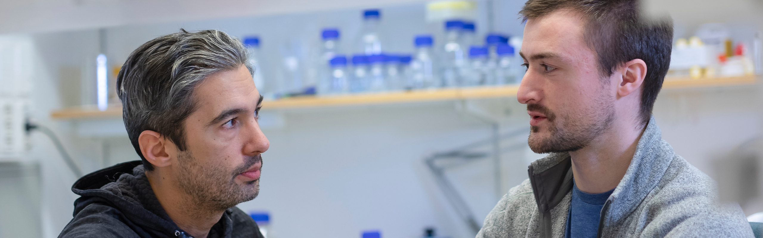 Bakom hylla med provrör står Felipe och Michael