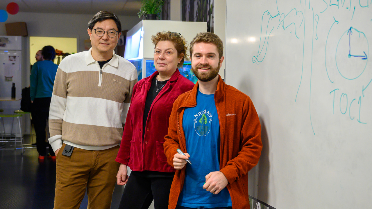A group of people standing next to a white board