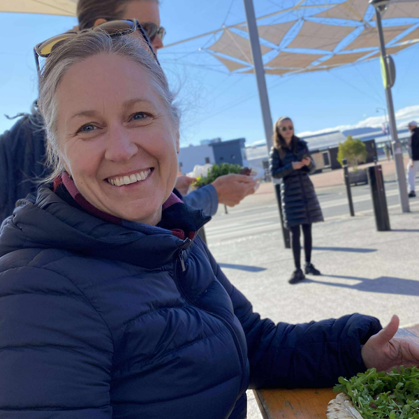 Kvinna med täckjacka sitter och äter smörgås.