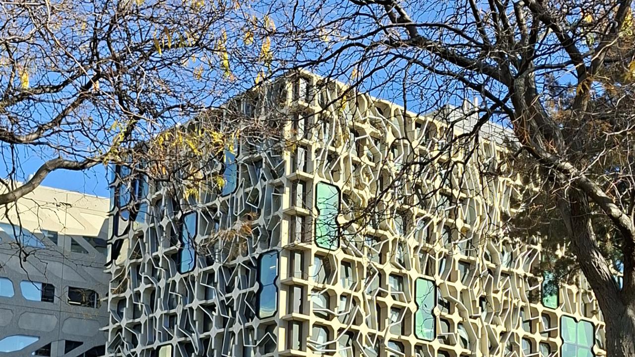 Byggnadsfasad med park i förgrunden.