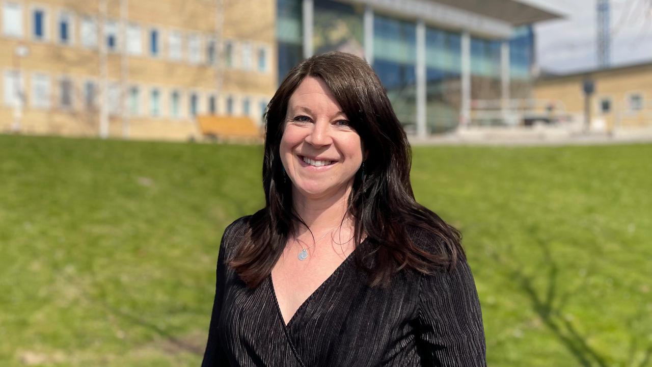 En kvinna i svart klänning står framför en byggnad.