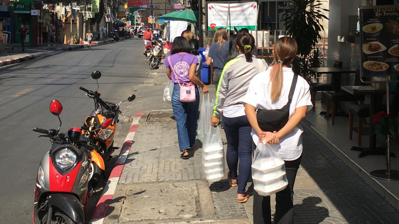 Personer med matpåsar går längs en gata.