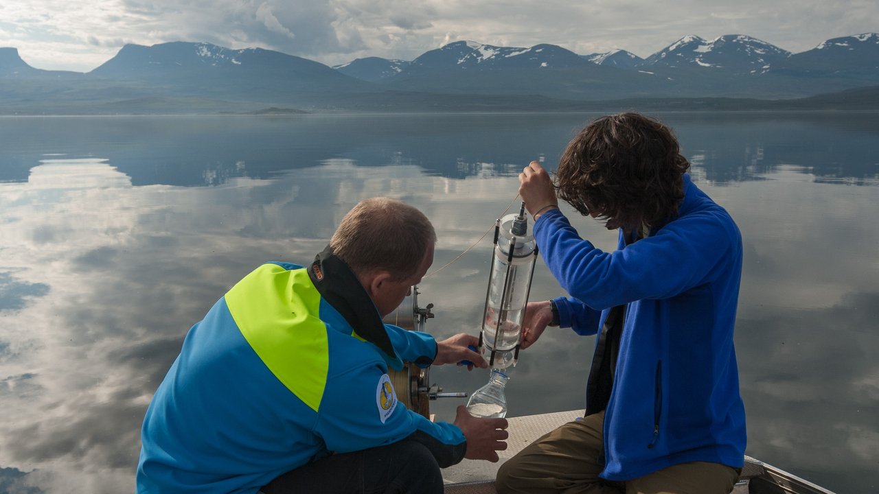 Forskare i fältarbete tar vattenprov i fjällsjö.