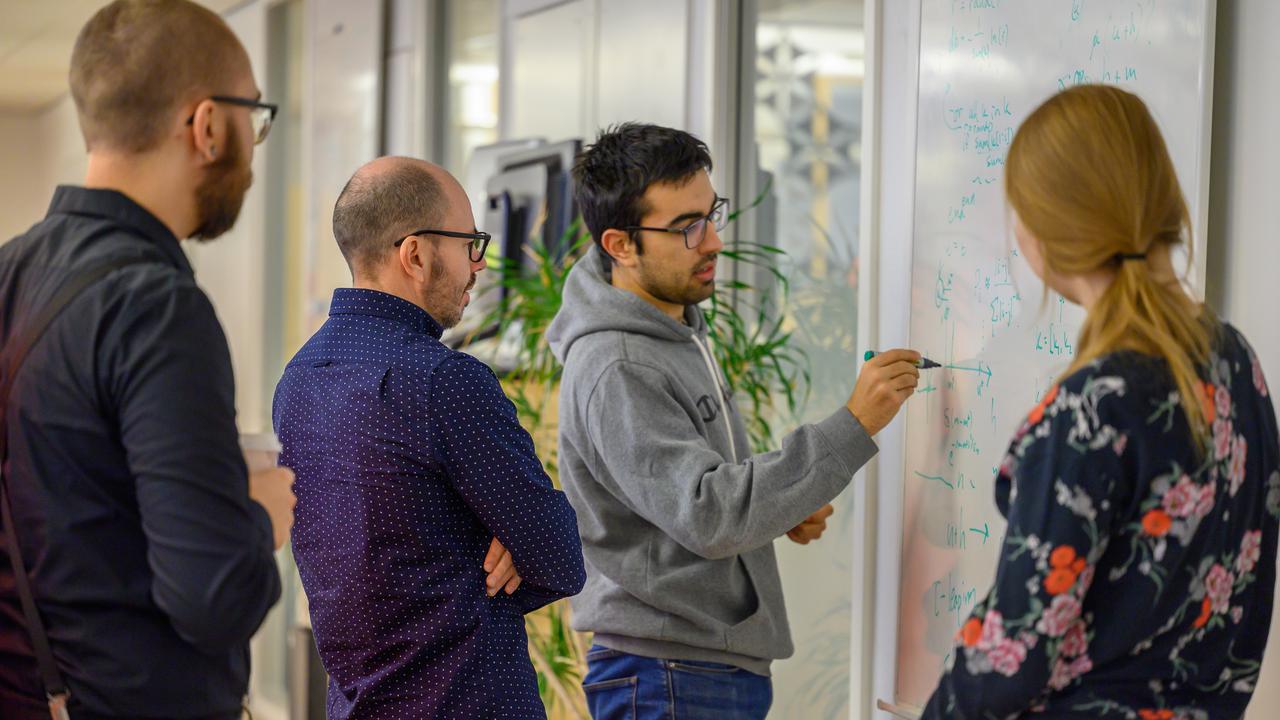 A group of people standing around a white board