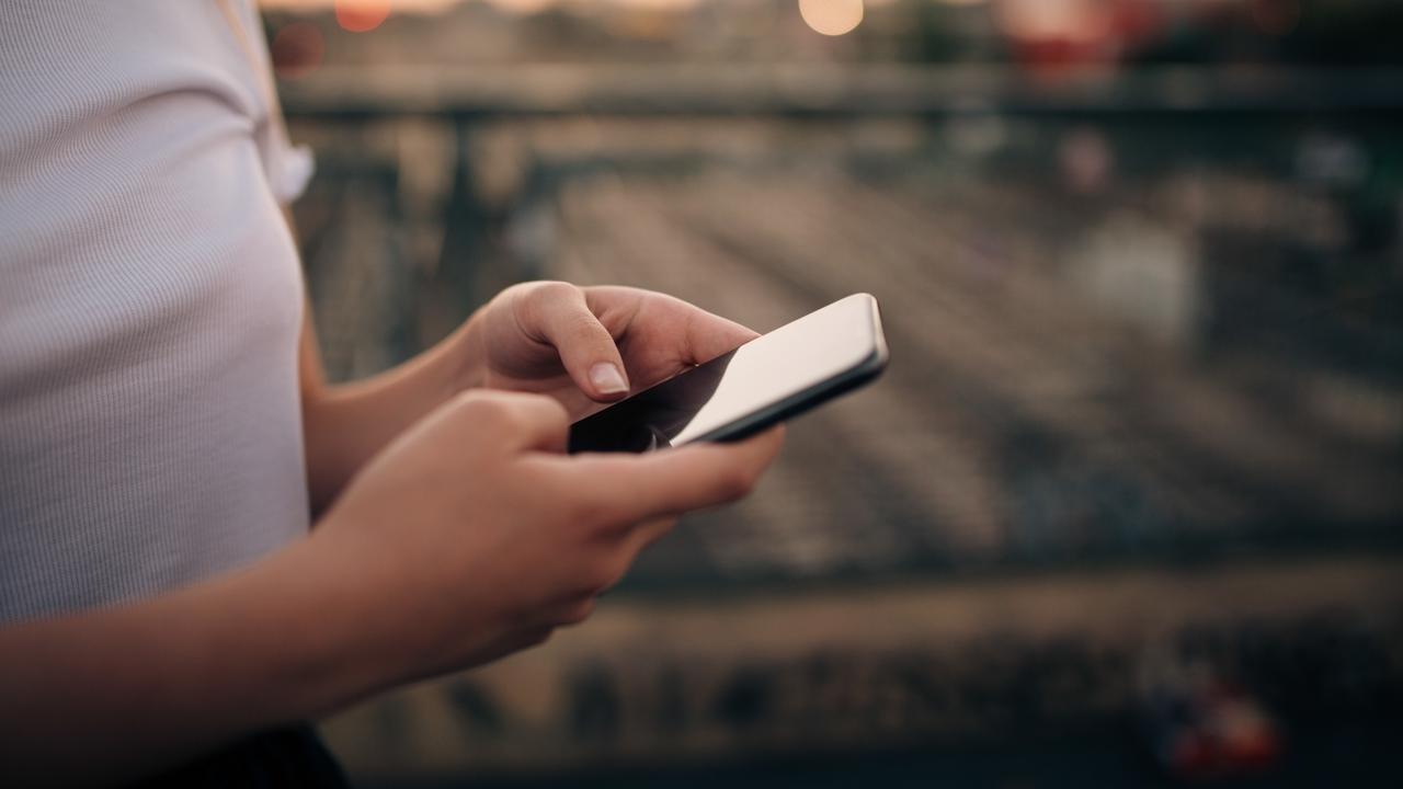 Bild på kvinna sedd från sidan med mobiltelefon i händerna