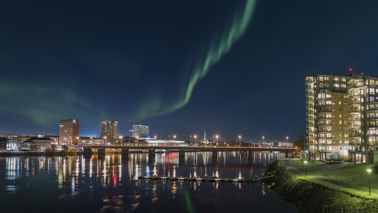 Umeå skyline med umeälven i förgrunden. Norrsken på himlen.