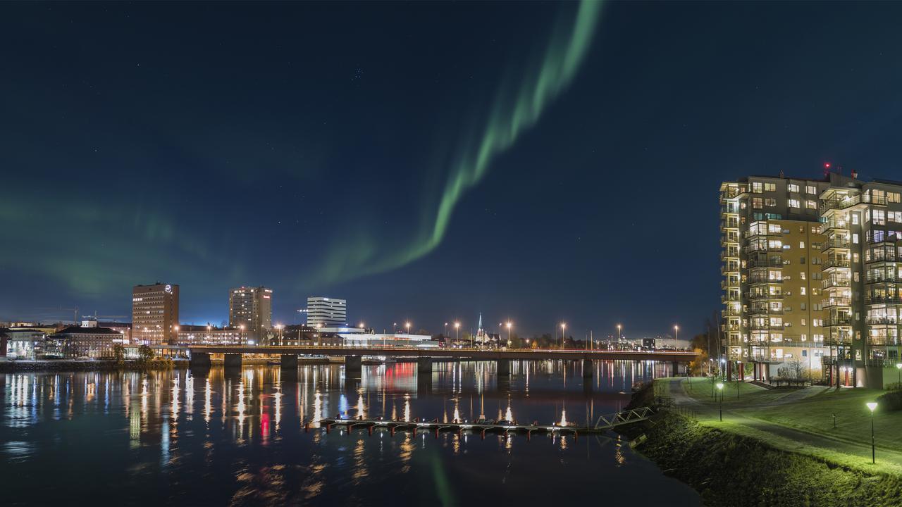 Umeå skyline med umeälven i förgrunden. Norrsken på himlen.