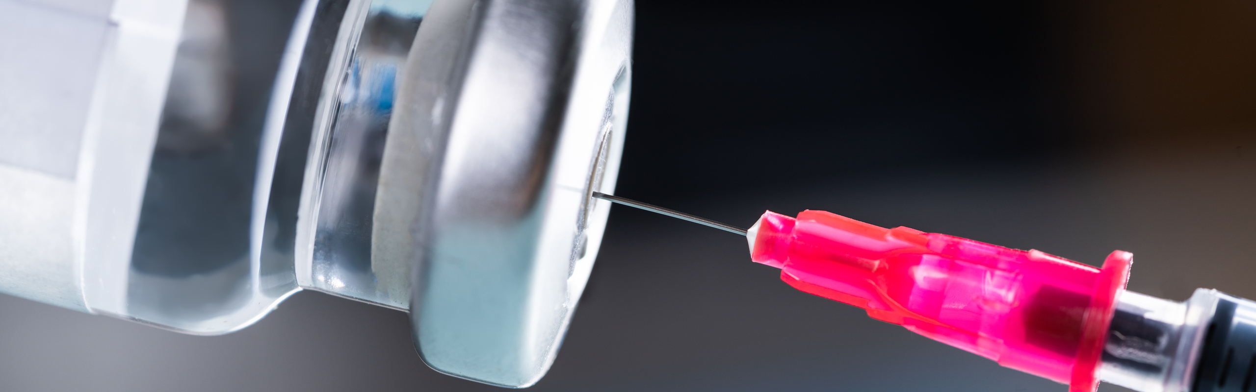 Nål som sticks in i behållare med vaccin.