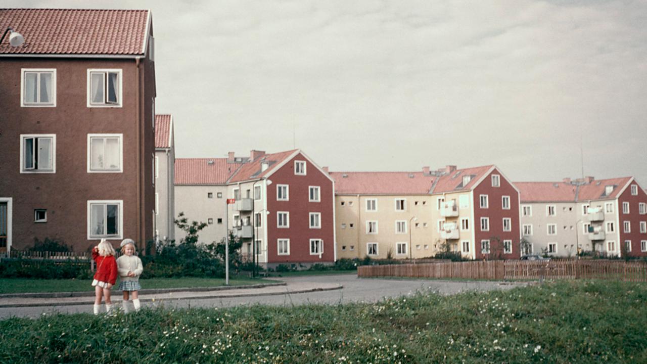 Två flickor står framför en rad med hus.