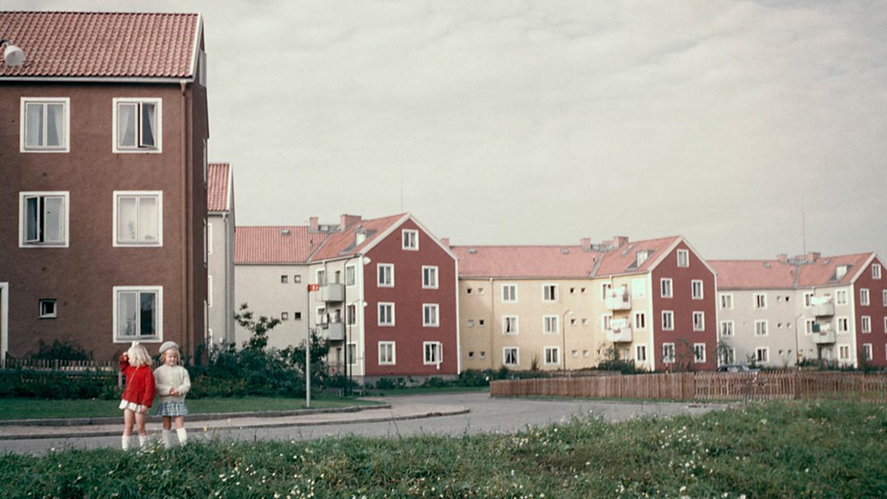 Två flickor står framför en rad med hus.