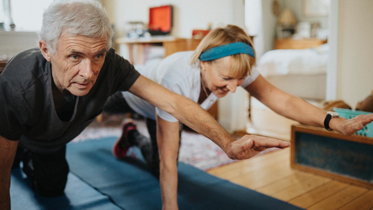 Äldre par gör yoga på matta