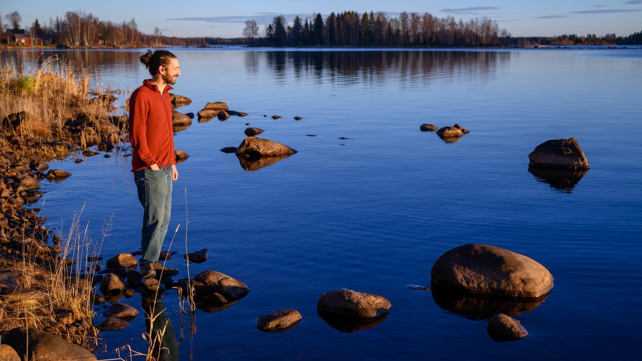A man standing on a rocky shore next to a body of water