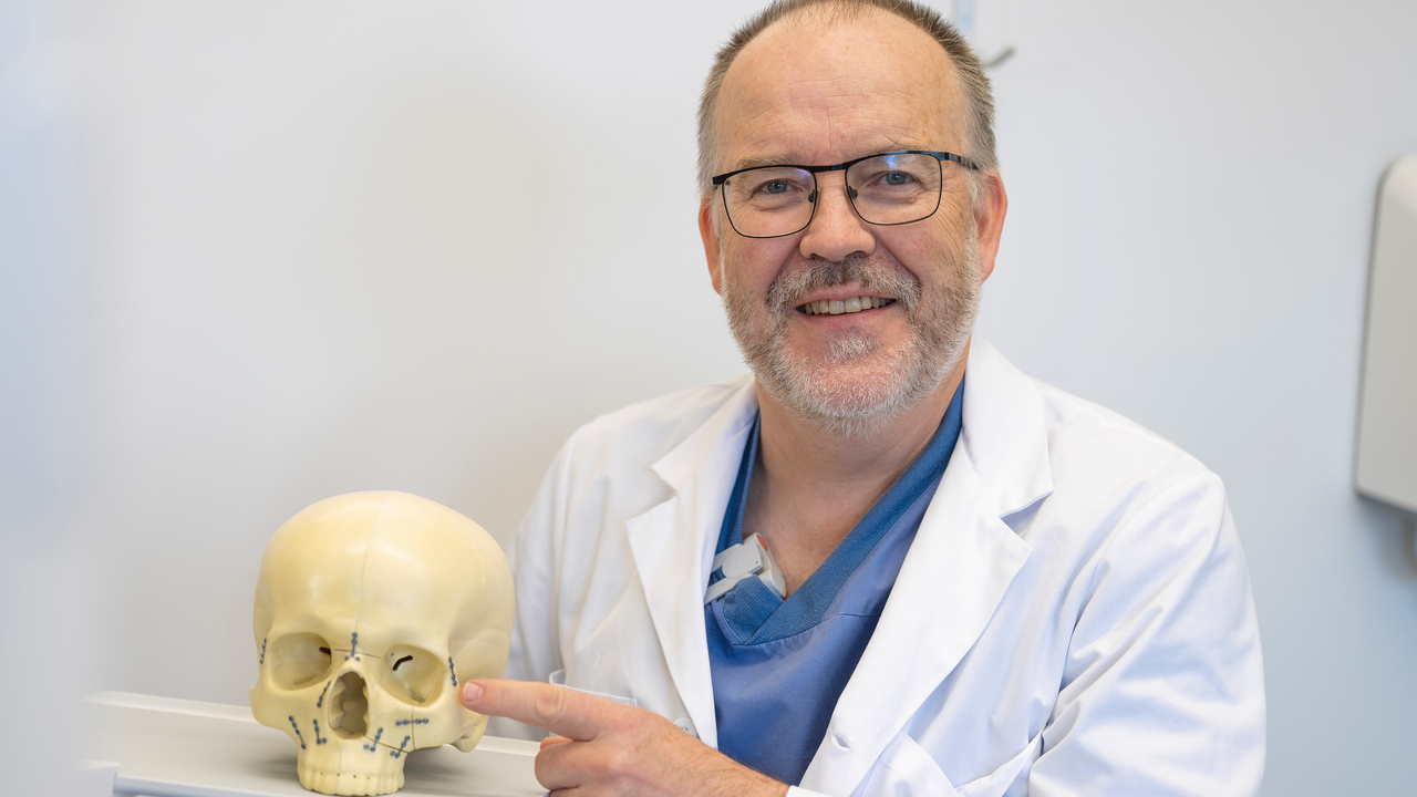 En man i labbrock pekar på en människoskalle