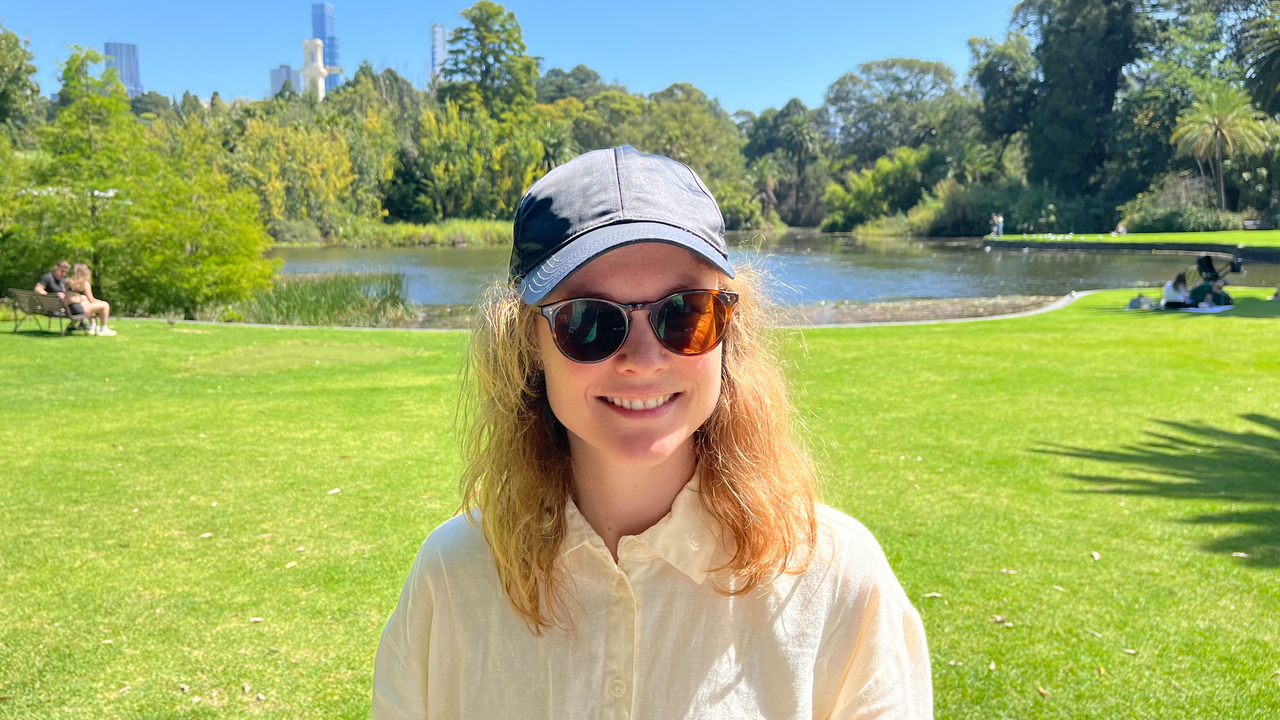 Kvinna i keps och solglasögon i den kungliga botaniska trädgården i Melbourne.