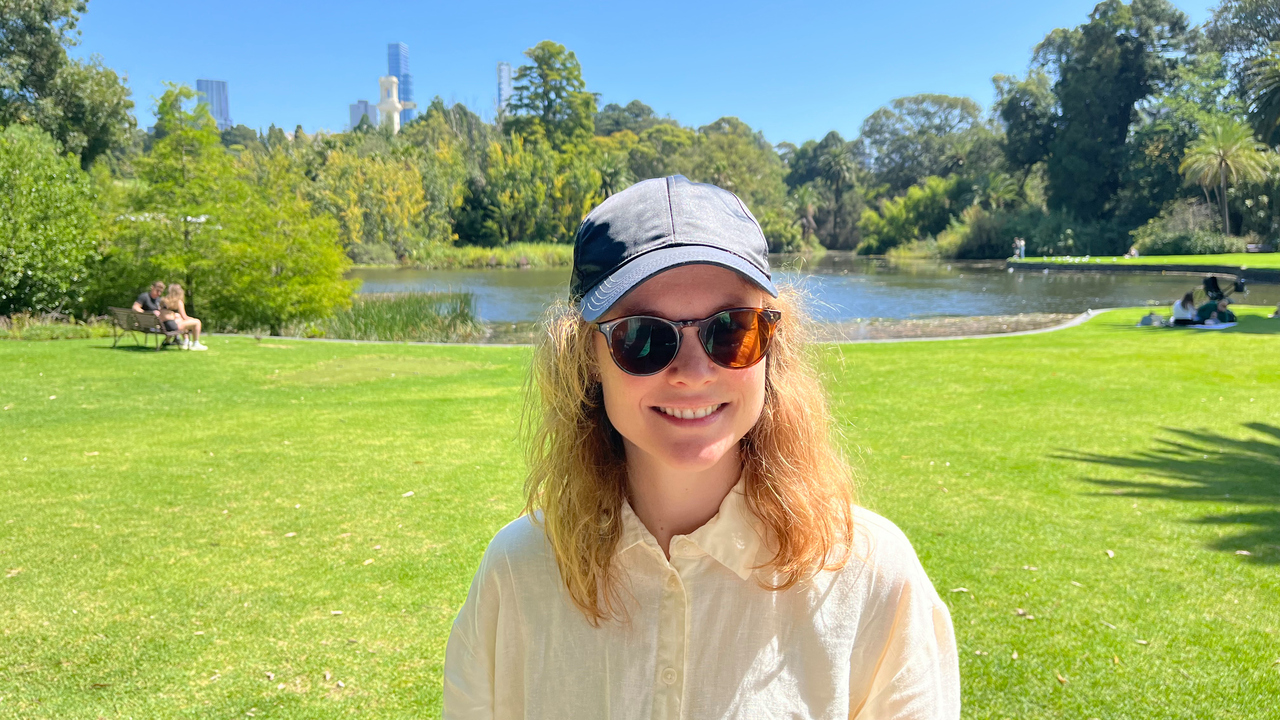 Kvinna i keps och solglasögon i den kungliga botaniska trädgården i Melbourne.