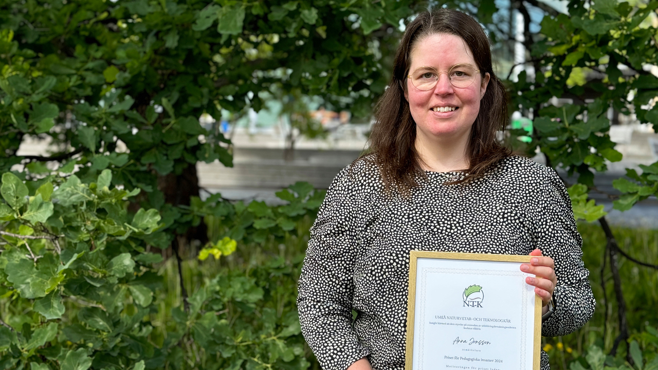 Anna Jonsson, universitetslektor i datavetenskap, har långt hår och glasögon. Hon står i en grönskande utemiljö, och håller i sitt diplom.