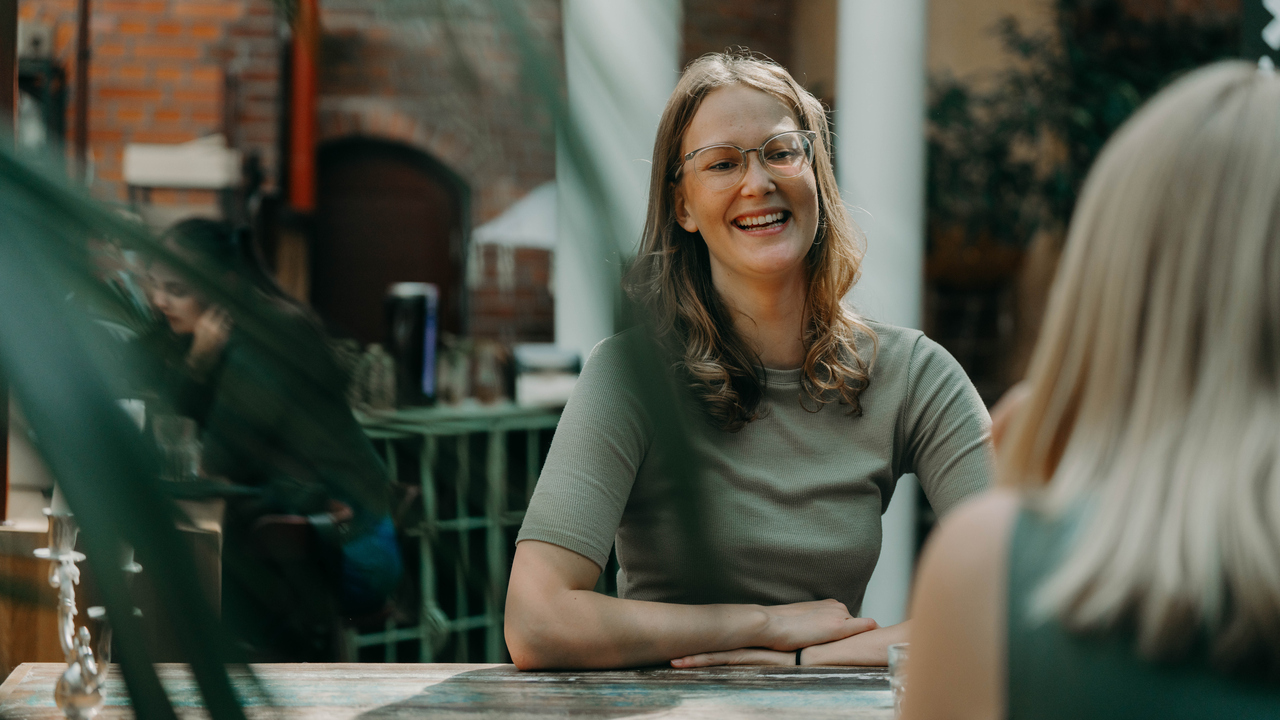 En kvinna sitter vid ett bord och skrattar.