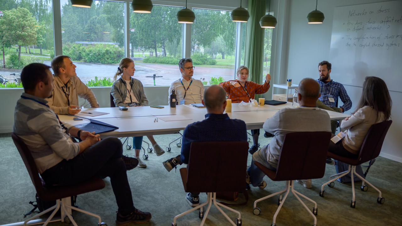 A group of researchers at a table talk together.