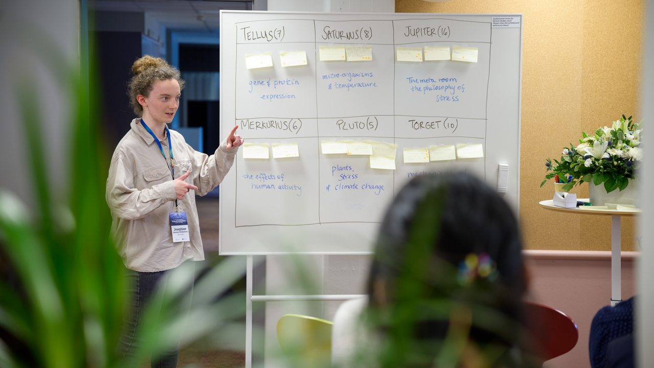 Josephine står bredvid en hel tavla med post-it-lappar och ämnen i rutor.